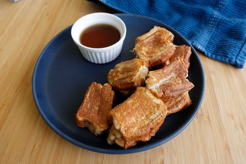 french toast with syrup in cup on wood surface with napkin